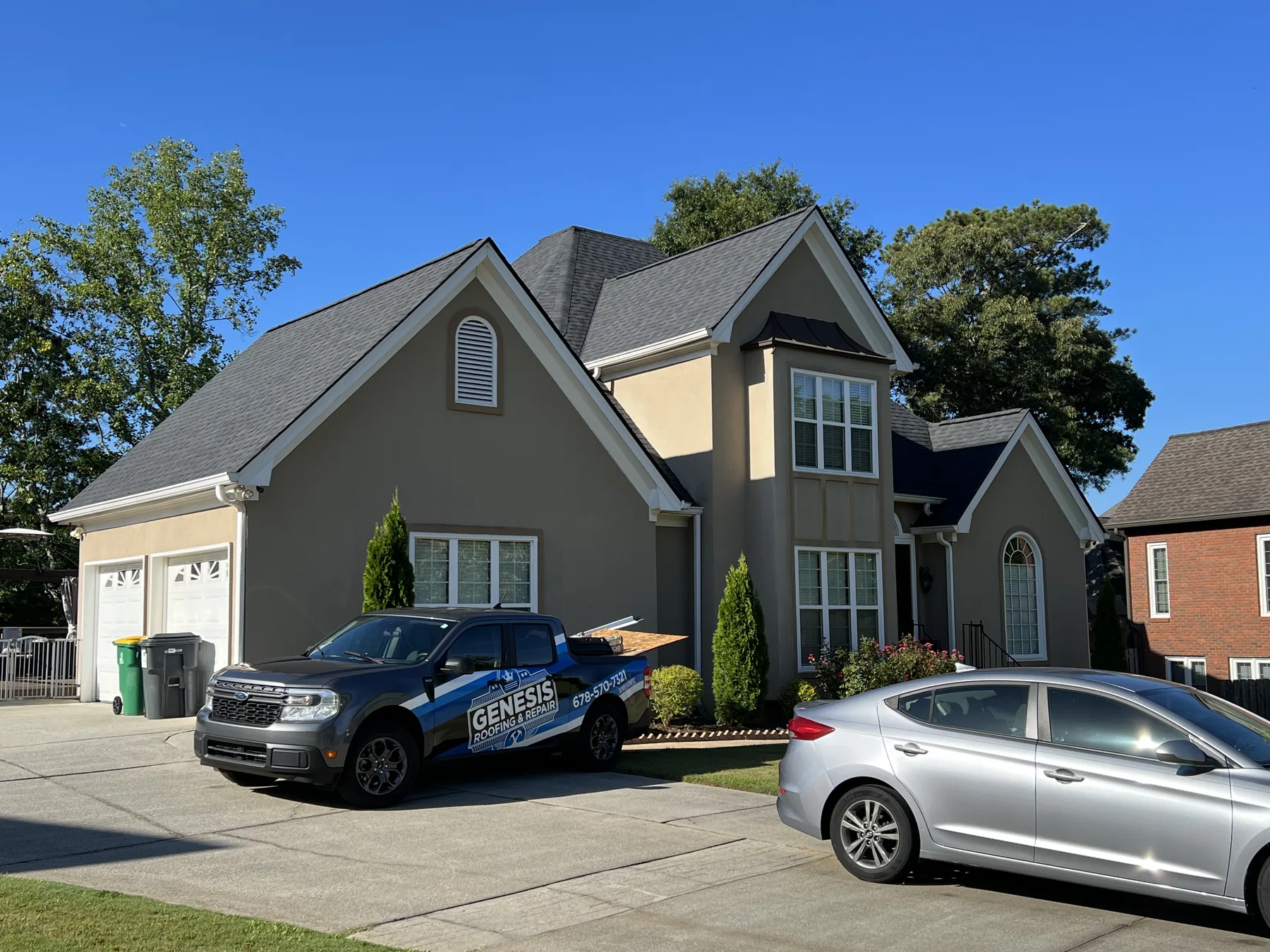 Dark shingle roof on a gray home with Genesis truck