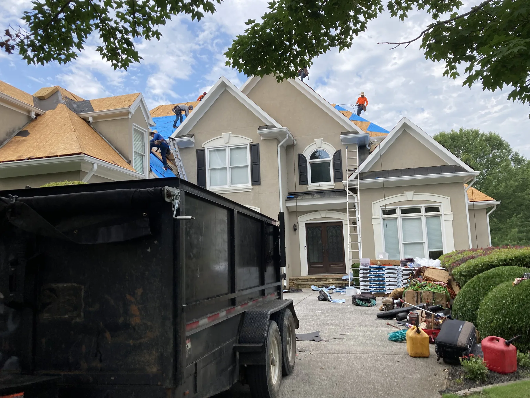Roofing crew working on a large light-colored home