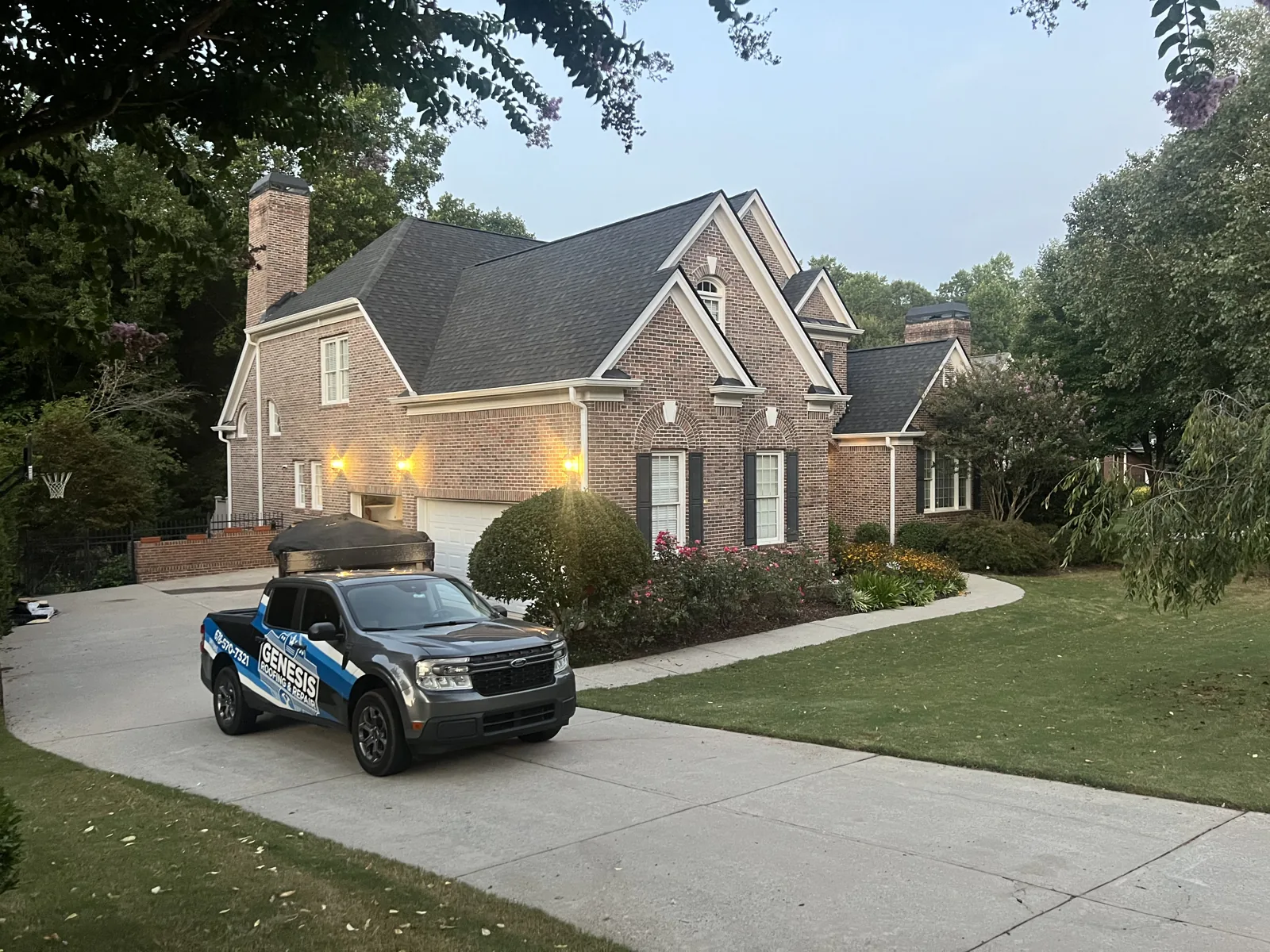 Finished roof on a brick home with the Genesis truck in the driveway