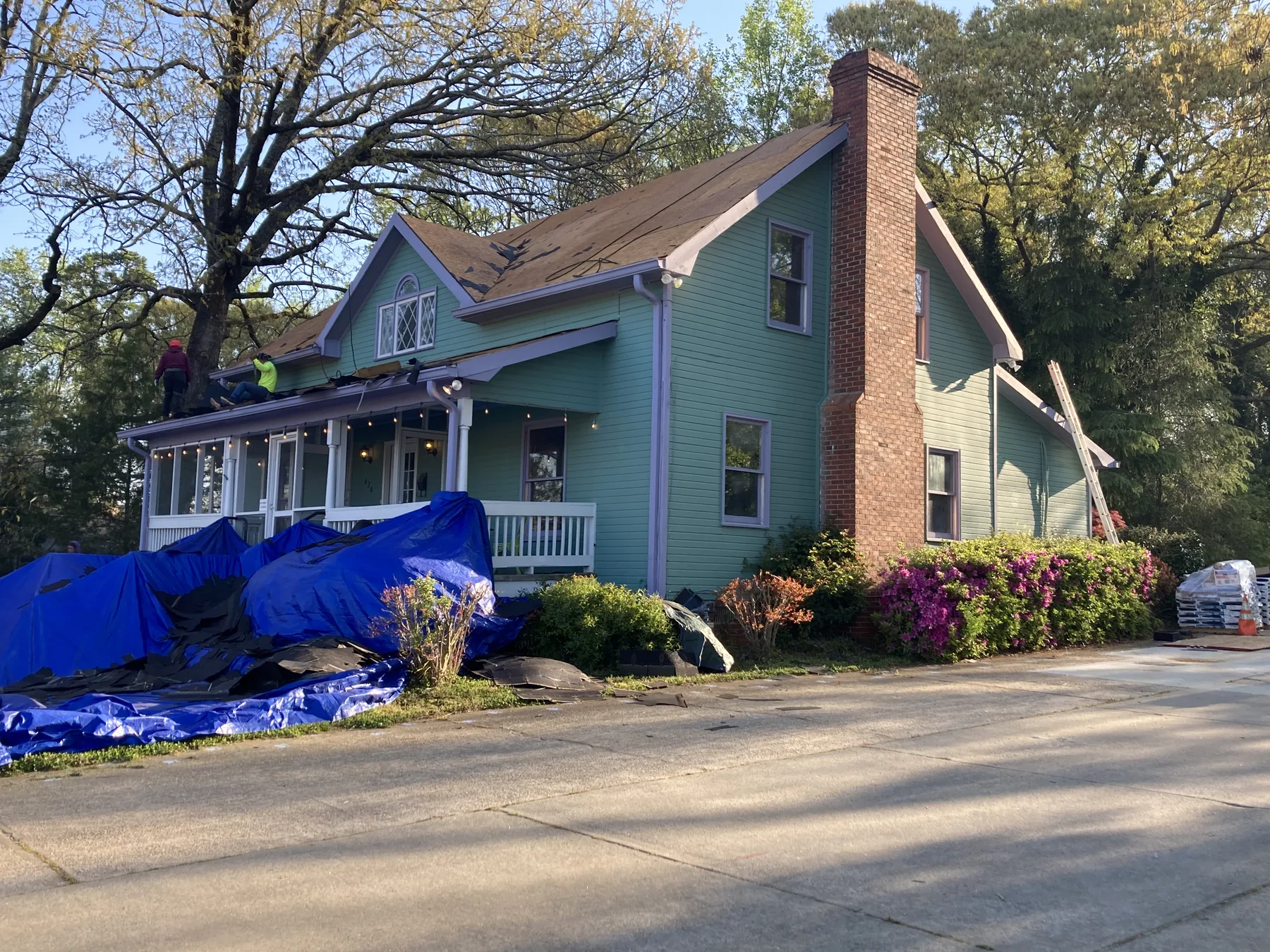 Roofing crew working on a home with a green exterior