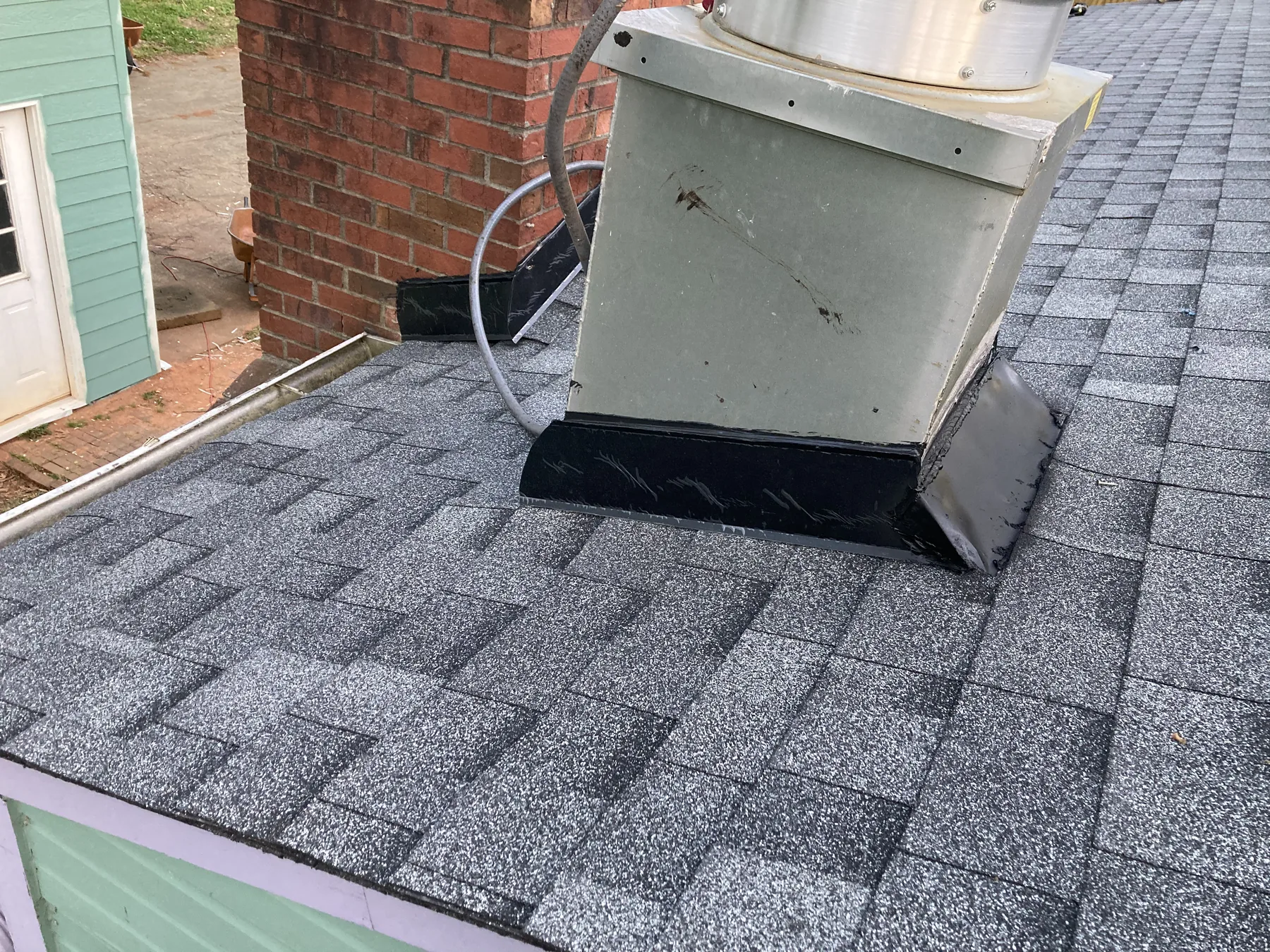 Close view of shingles and flashing around a roof vent