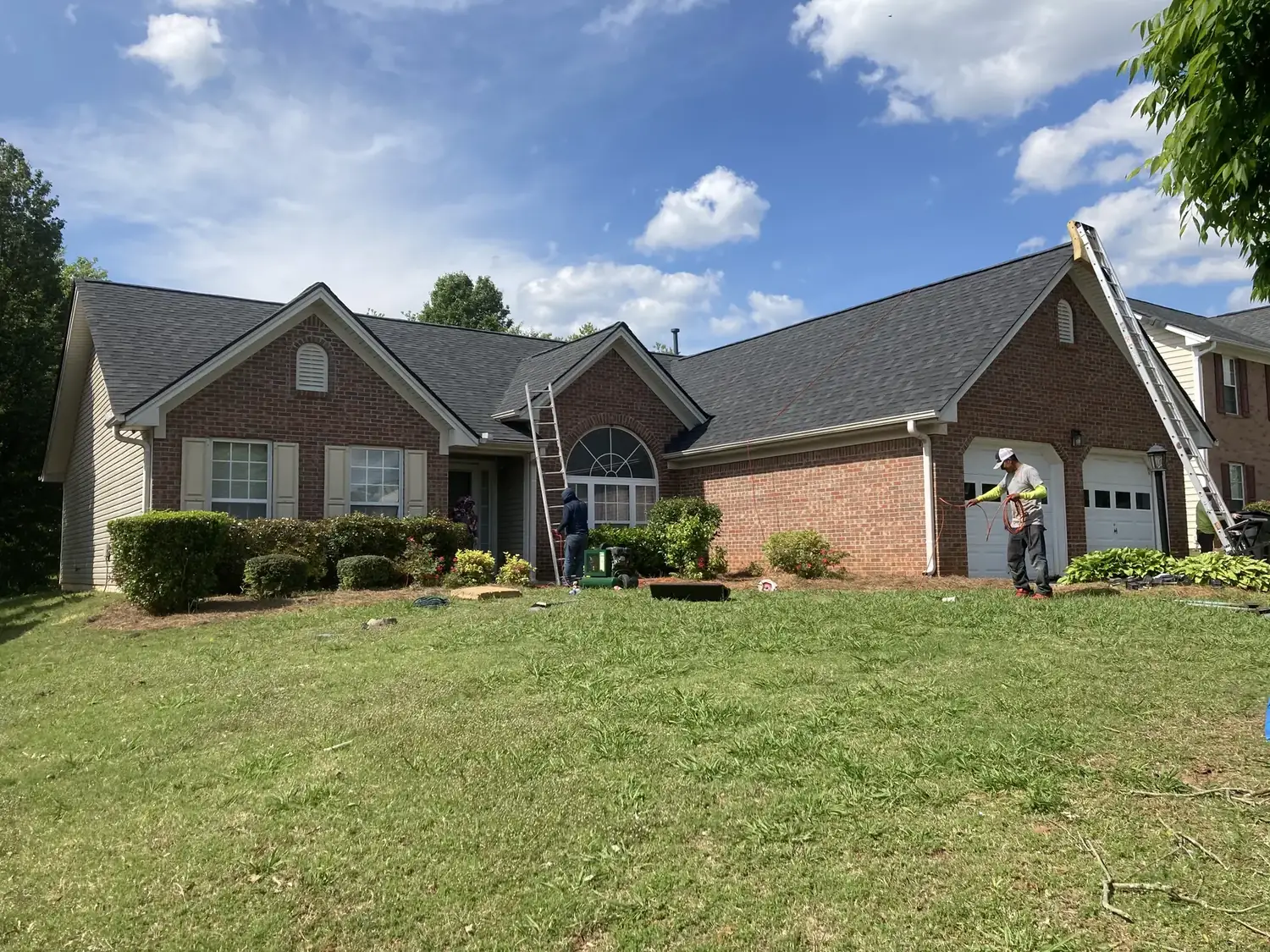Finished shingle roof on a brick home viewed from the front lawn