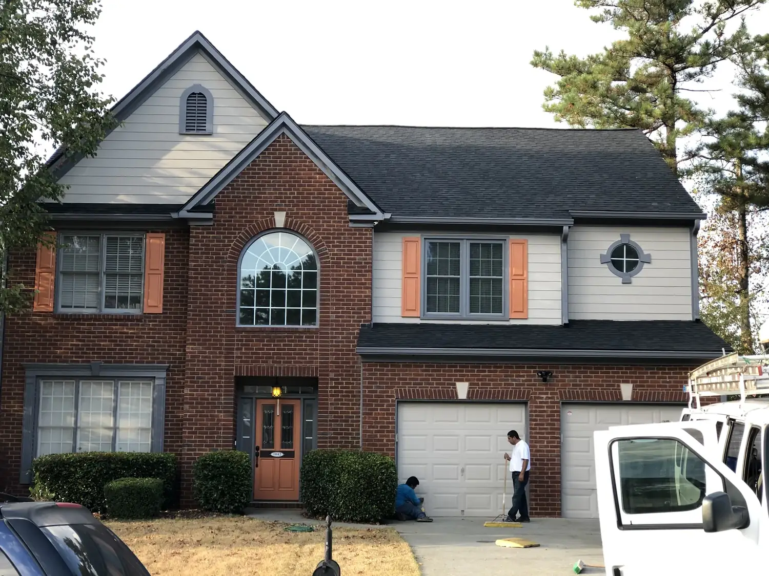 Roofing crew at a two-story brick home