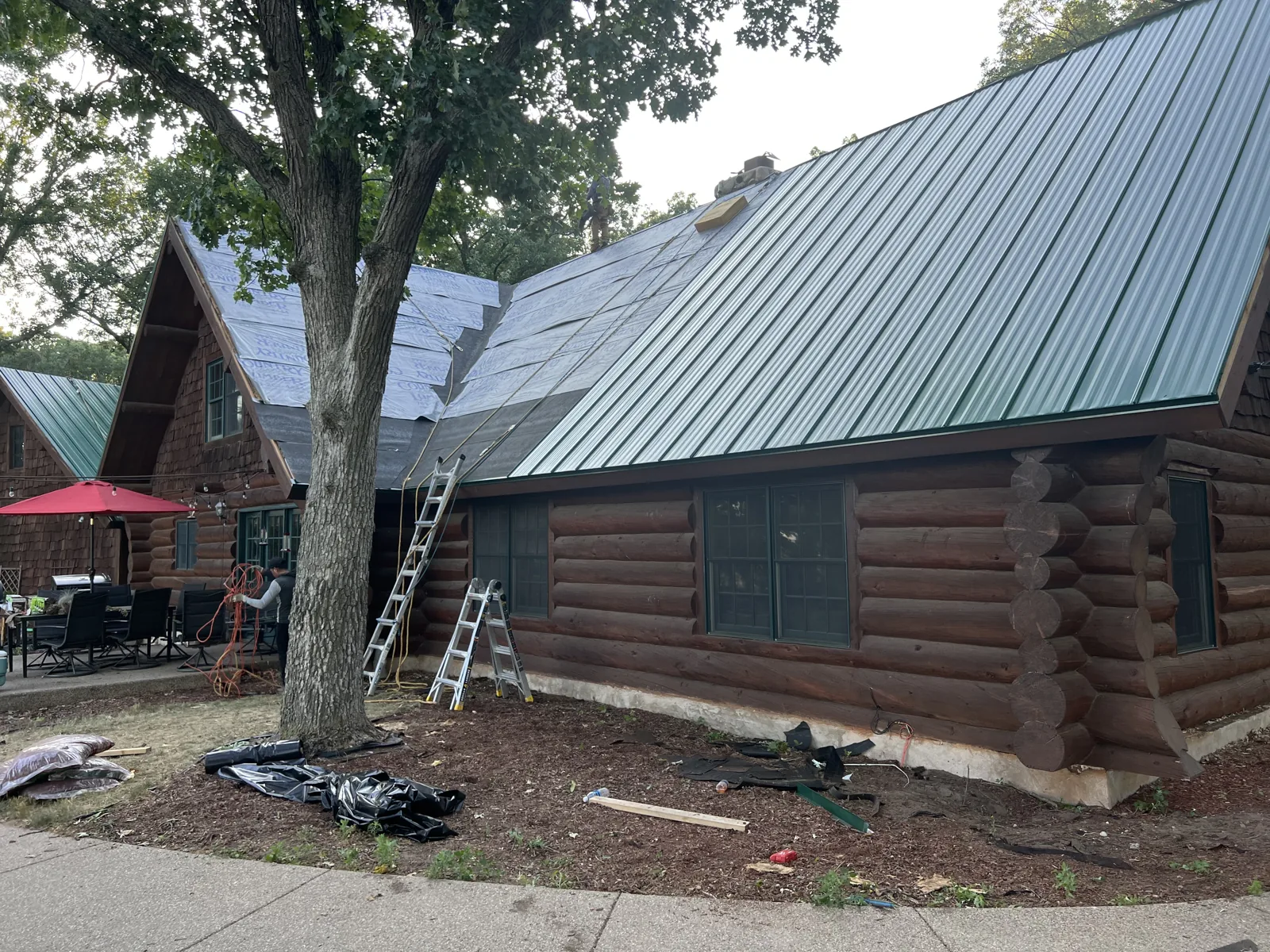 Green metal panels being installed on the log home